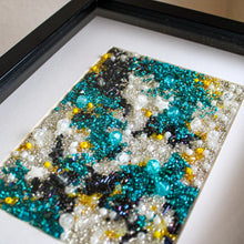Load image into Gallery viewer, Framed artwork made of beads with a black, blue, and yellow pattern on a white background.