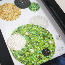 Load image into Gallery viewer, Decorative round embellishments in various colors and textures on a white background, framed in black.
