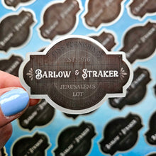 Load image into Gallery viewer, Sticker with 'Barlow &amp; Straker' branding held over a patterned background
