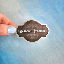 Load image into Gallery viewer, Hand holding a Barlow &amp; Straker sticker against a blue textured background
