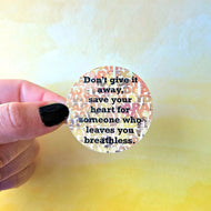 Round sticker with motivational quote held by a hand against a blurred background