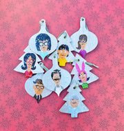 Set of eight Christmas ornaments featuring hand-painted characters from the TV show 'Bob's Burgers'. Each ornament has a snow effect and is equipped with a green ribbon for hanging.